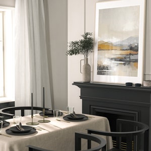 May include: A dining room table setting with a beige linen tablecloth, black chairs, and gold flatware. Two black candlesticks with black candles are on the table. A framed abstract landscape painting hangs above a black fireplace.