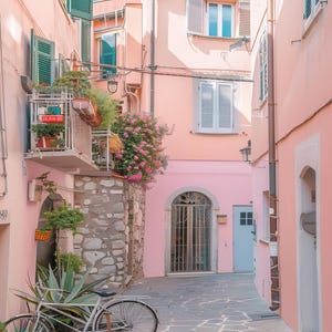 May include: A narrow, cobblestone alleyway in a European city with pink buildings and a bicycle parked on the side. The buildings have white shutters and a wrought iron gate.