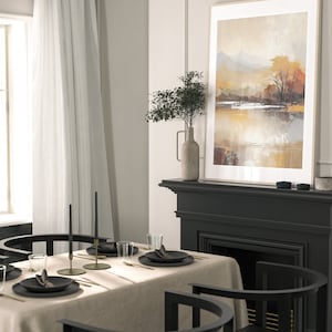 May include: A dining room table setting with a beige linen tablecloth, black chairs, and gold flatware. Two black candlesticks with black candles are on the table. A framed abstract landscape painting hangs above a black fireplace.