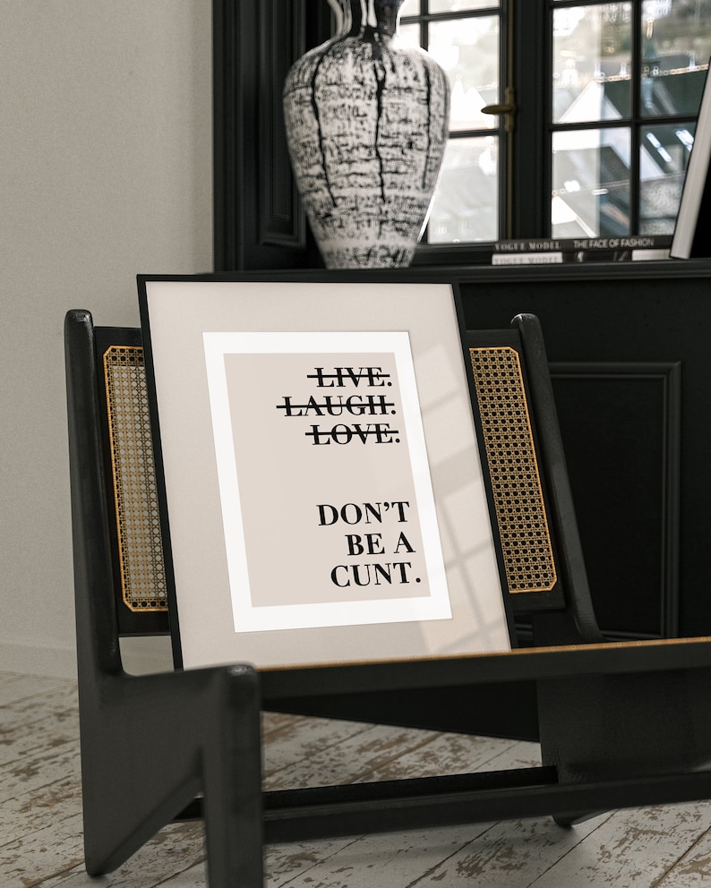 May include: A black framed print with a beige background and black text that reads "LIVE. LAUGH. LOVE. DON'T BE A CUNT."