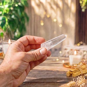 May include: A clear, faceted quartz crystal point with a pointed tip and a hexagonal base. The crystal is transparent with visible internal inclusions and natural fractures, reflecting light through its smooth, polished surfaces.
