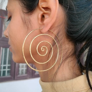 Peut inclure: Grandes boucles d'oreilles en or en forme de spirale. Les boucles d'oreilles sont en métal martelé et ont une finition texturée.
