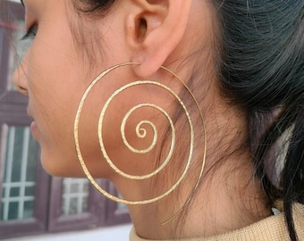 May include: Large gold spiral hoop earrings. The earrings are made of hammered metal and have a textured finish.