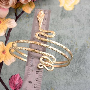 Könnte beinhalten: Goldfarbenes Schlangenarmband mit doppeltem Wickeldesign. Das Armband hat einen Durchmesser von etwa 7,6 cm.