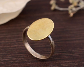 May include: A gold oval ring with a smooth, flat top. The ring is made of brass and has a simple, minimalist design.