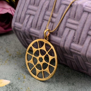 May include: A gold-toned necklace with a circular pendant featuring a geometric design. The pendant is made of a delicate, openwork pattern with a star-shaped centre.