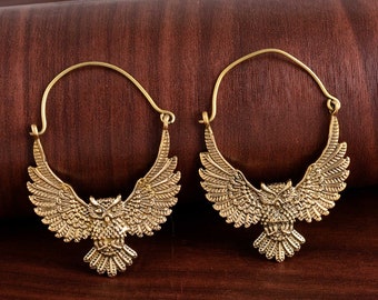 May include: A pair of gold hoop earrings with an owl design. The owls have spread wings and are facing forward.