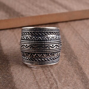 Peut inclure: Une bague en argent avec une large bande orn&eacute;e d'un motif g&eacute;om&eacute;trique complexe. Le design comprend une s&eacute;rie de lignes ondul&eacute;es, de triangles et de points.