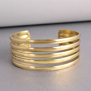 May include: A gold-toned metal cuff bracelet with five bands.