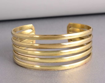 May include: A gold-toned metal cuff bracelet with five bands.