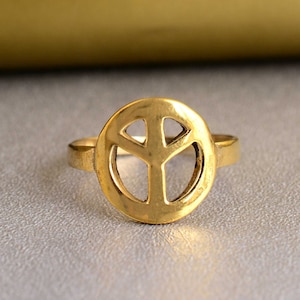 May include: A gold peace sign ring. The ring is made of metal and has a simple design.