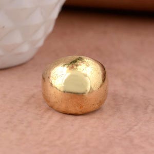 Könnte beinhalten: Ein großer, runder Ring in Goldfarbe. Der Ring ist glatt und hat eine glänzende Oberfläche.