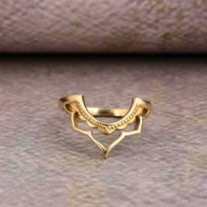 May include: A gold ring with a delicate, intricate design. The ring is open at the front and has a scalloped edge.
