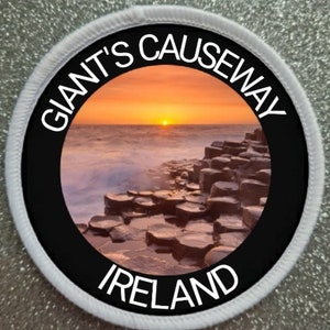 May include: Circular patch featuring a sunset over the Giant's Causeway in Ireland. The image shows the hexagonal basalt columns and the ocean. The text "GIANT'S CAUSEWAY" and "IRELAND" are in white lettering on a black background.