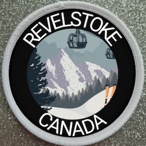 May include: A white and black circular patch with the text "Revelstoke Canada" and a graphic of a snowy mountain scene with ski lifts and skiers.