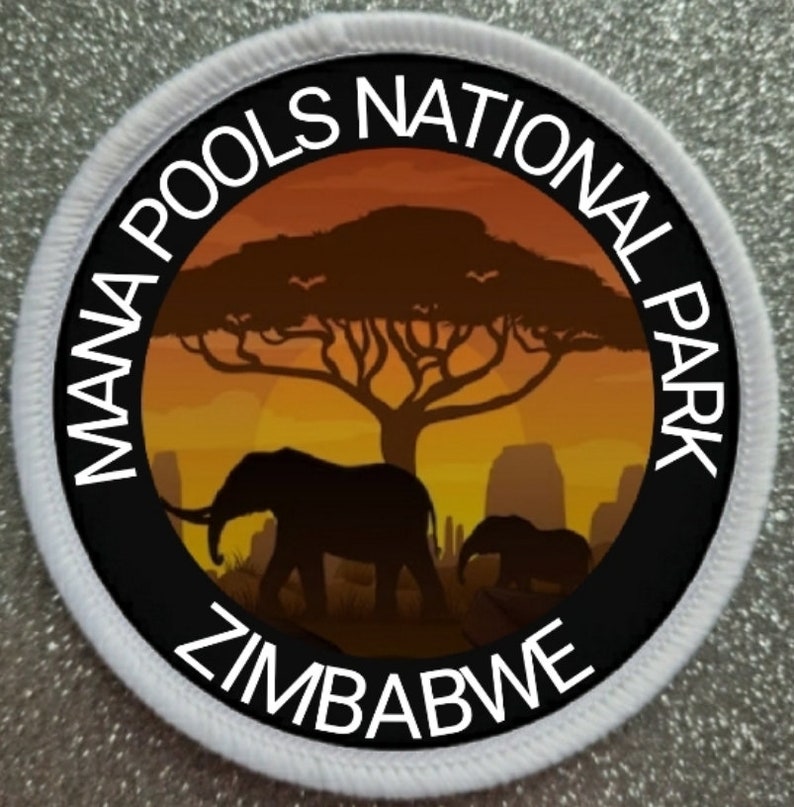May include: A white round patch with black text and a silhouette of an elephant and a tree. The text reads "Mana Pools National Park Zimbabwe".