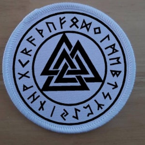 Puede incluir: Parche redondo blanco con un símbolo Valknut negro rodeado por un círculo de runas negras. Las runas están en un patrón circular y todas miran en la misma dirección.