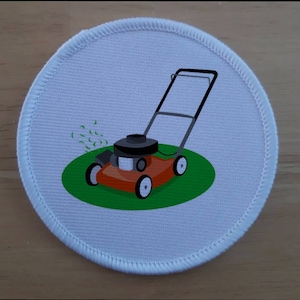 Könnte beinhalten: Ein kreisförmiger bestickter Aufnäher mit weißem Hintergrund und gesticktem Rand. Das Motiv zeigt einen roten Rasenmäher auf einer grünen kreisförmigen Grasfläche, mit kleinen grünen geschwungenen Linien, die Grasschnitt darstellen.