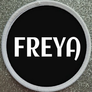 May include: White round patch with a black circle in the center. The text "FREYA" is written in white on the black circle.