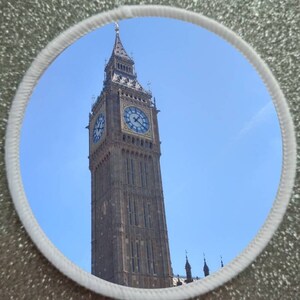 May include: A close-up view of Big Ben, the iconic clock tower in London, England. The tower is made of stone and has a large clock face with Roman numerals. The sky is blue and clear.