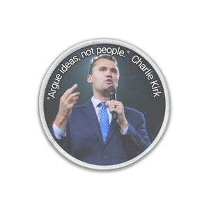 May include: A circular patch with a man in a suit holding a microphone. The patch features the quote "Argue ideas, not people." by Charlie Kirk. The patch has a white border and a black background.