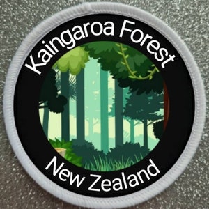 Op de afbeelding: Een witte ronde patch met zwarte tekst en een zwarte cirkel in het midden. De tekst luidt "Kaingaroa Forest New Zealand". De zwarte cirkel bevat een groene en bruine illustratie van een bos.