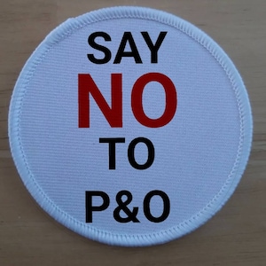 Op de afbeelding: Ronde witte stoffen badge met de tekst "SAY NO TO P&O" in zwarte en rode letters.