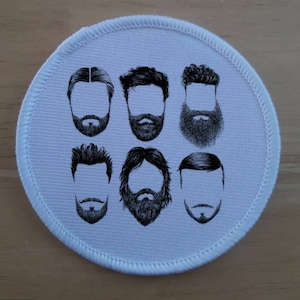以下が含まれることがあります： 白地に黒と白の6つの異なるひげのスタイルのイラストが描かれた丸いパッチ