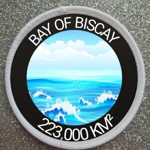 May include: White round patch with black border and text "BAY OF BISCAY" and "223,000 KM²". The patch features a blue ocean with white waves and a blue sky with white clouds.