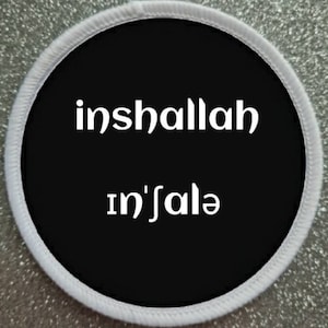 Puede incluir: Parche redondo blanco y negro con el texto "inshallah" e "in'shalla" en blanco.