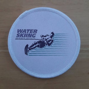 May include: White round patch with a blue silhouette of a person water skiing. The text "WATER SKIING SUMMER SPORTS" is printed in blue above the silhouette.