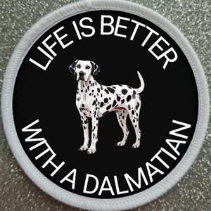 Puede incluir: Un parche redondo blanco y negro con un borde blanco. El parche tiene el texto "Life is better with a Dalmatian" en un círculo blanco sobre un fondo negro. Un dálmata blanco y negro está de pie en el centro del círculo.