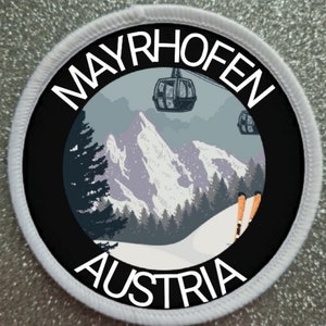 Könnte beinhalten: Runder Aufnäher mit dem weißen Schriftzug "MAYRHOFEN AUSTRIA", der eine Berglandschaft umrahmt. Die Szene zeigt eine Seilbahn, schneebedeckte Berge und Kiefern, mit einem schwarzen Rand und weißen Nähten.