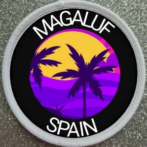 Op de afbeelding: Een ronde witte patch met zwarte tekst en een afbeelding van een zonsondergang met palmbomen. De tekst luidt "MAGALUF SPANJE".