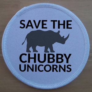 May include: White round patch with black text that reads "Save the Chubby Unicorns". A black silhouette of a rhinoceros is in the center of the patch.