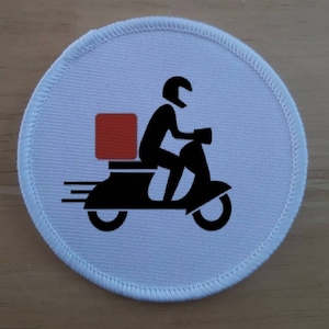 May include: White round patch with a black and white illustration of a person riding a scooter with a red box on the back. The scooter has a speed line behind it.