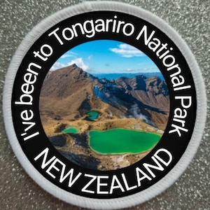May include: A white round patch with black text and a photo of a mountain range with green lakes. The text reads "I've been to Tongariro National Park NEW ZEALAND".