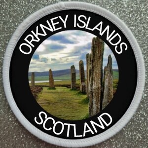 May include: A white round patch with black text and a photo of standing stones in a field. The text reads "ORKNEY ISLANDS SCOTLAND".