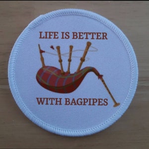 May include: White round patch with red text that reads "Life is better with bagpipes". A cartoon image of a set of bagpipes is in the centre of the patch.