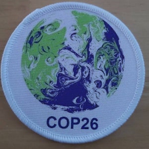 May include: White round patch with a blue and green marbled globe design and the text "COP26" in blue.