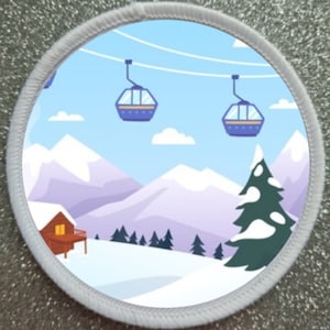 Puede incluir: Un parche circular blanco con una escena de invierno. La escena incluye una cordillera nevada, una pequeña cabaña, un pino y tres teleféricos en el cielo. El cielo es azul con nubes blancas.