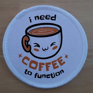 Peut inclure: Patch rond blanc avec une tasse de café de dessin animé noir et blanc avec un liquide brun à l'intérieur. Le texte "i need coffee to function" est imprimé en orange et noir.