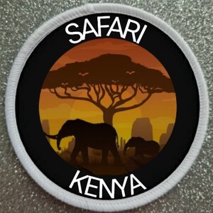 May include: A white round patch with black text that says "SAFARI KENYA". The patch has a black circle in the centre with a silhouette of an African savanna sunset with a large tree and two elephants.
