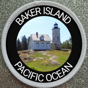 Könnte beinhalten: Ein runder weißer und schwarzer Patch mit dem Text "BAKER ISLAND PACIFIC OCEAN" am Rand. Die Mitte des Patches zeigt ein Foto eines weißen Leuchtturms und eines weißen Hauses mit einem grünen Rasen und blauem Himmel im Hintergrund.