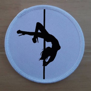 May include: White round patch with a black silhouette of a person on a pole.
