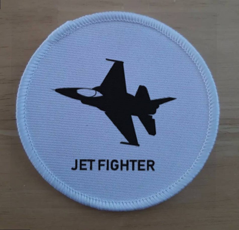 Op de afbeelding: Een witte ronde patch met een zwart silhouet van een straaljager en de tekst "JET FIGHTER" eronder gedrukt.