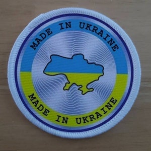May include: Round patch with a white border and the words "MADE IN UKRAINE" in blue text. The center features a map of Ukraine in blue and yellow, the colors of the Ukrainian flag.
