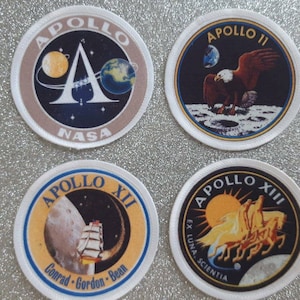 May include: Four round embroidered patches featuring the Apollo mission logos. The patches are white with blue, yellow, and red accents. The patches feature the text "Apollo", "NASA", "Conrad-Gordon-Bean", "EX LUNA, SCIENTIA", and the Roman numerals "II", "XII", and "XIII".