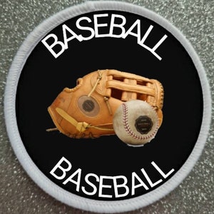 May include: A white and black circular patch with the word "BASEBALL" written in white around the edge. The center of the patch is black and features a brown baseball glove and a white baseball with red stitching.