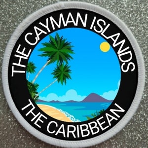 Peut inclure: Un écusson rond blanc avec du texte noir qui dit "The Cayman Islands The Caribbean" autour d'un cercle noir avec un ciel bleu, des nuages blancs, un soleil jaune, des palmiers, une plage et une montagne violette en arrière-plan.